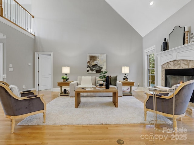 living room featuring light hardwood / wood-style flooring, a tile fireplace, and high vaulted ceiling