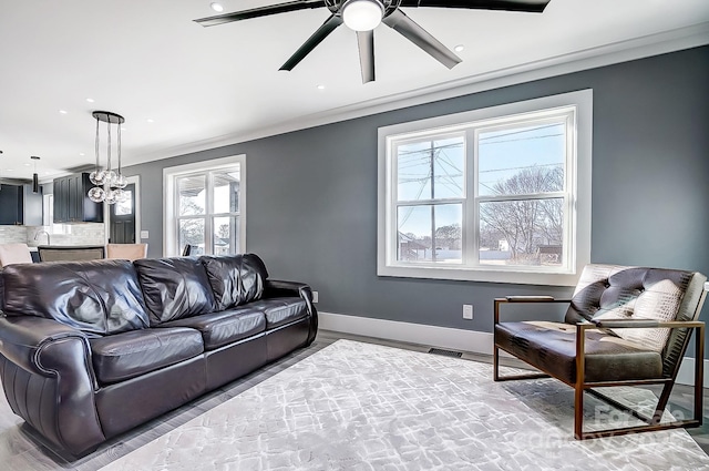 living room with ceiling fan with notable chandelier and crown molding