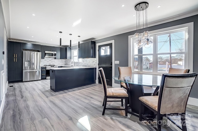 dining space with ornamental molding and light hardwood / wood-style floors