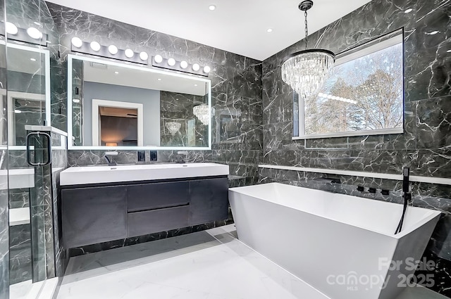 bathroom featuring tile walls, a tub to relax in, vanity, and a notable chandelier