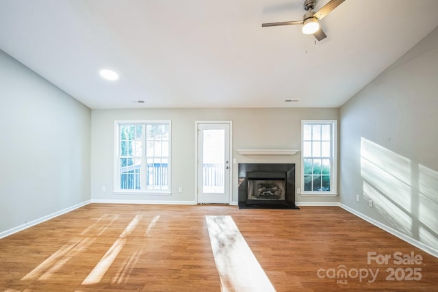 unfurnished living room with plenty of natural light, ceiling fan, and hardwood / wood-style floors