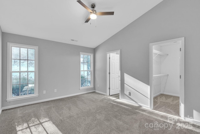 unfurnished bedroom with vaulted ceiling, a spacious closet, ceiling fan, a closet, and light colored carpet