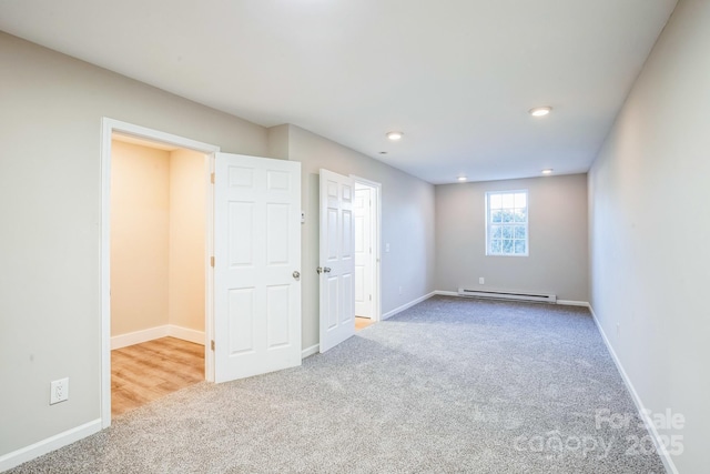 spare room featuring a baseboard radiator and light carpet