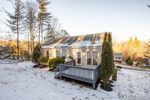 snow covered house featuring a wooden deck