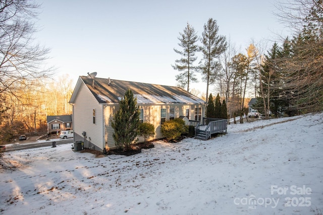 view of snowy exterior featuring a deck and central AC unit