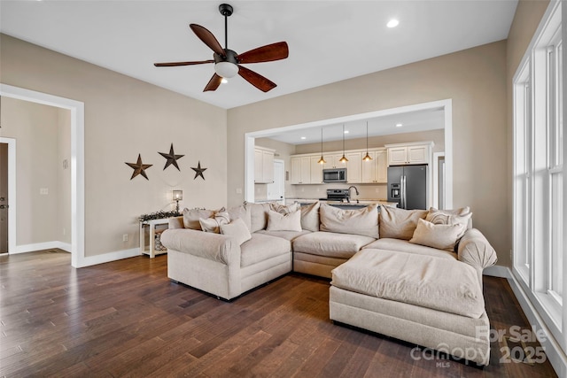 living room with dark wood-type flooring, ceiling fan, and sink