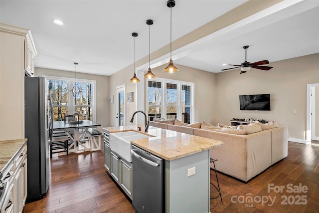 kitchen featuring decorative light fixtures, white cabinets, stainless steel appliances, and a kitchen island with sink