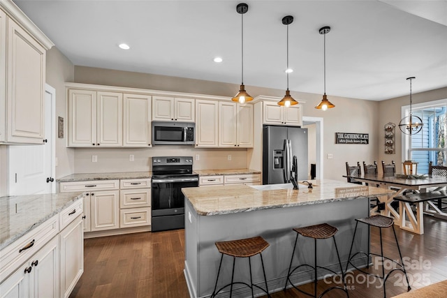 kitchen featuring stainless steel appliances, a kitchen island with sink, a kitchen breakfast bar, pendant lighting, and light stone counters