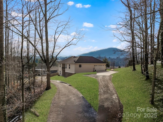 exterior space with a garage, a lawn, and a mountain view