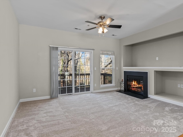 unfurnished living room featuring light colored carpet, built in features, and ceiling fan