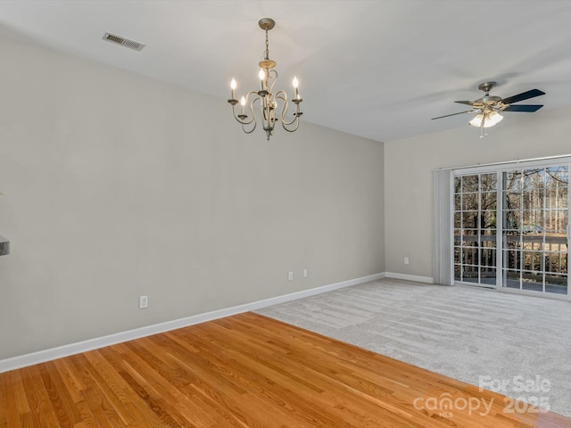 unfurnished room with ceiling fan with notable chandelier and hardwood / wood-style floors