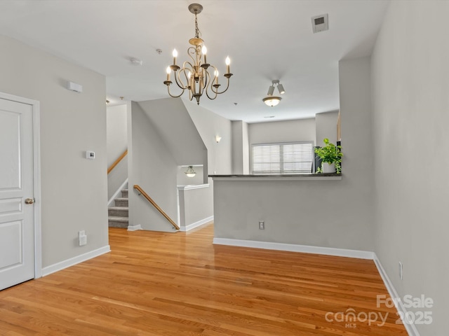 unfurnished dining area featuring an inviting chandelier and hardwood / wood-style flooring