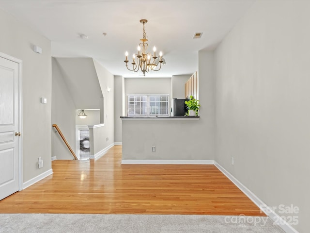 unfurnished dining area with light colored carpet and a chandelier