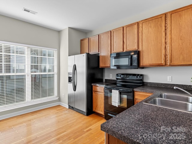 kitchen featuring sink, light hardwood / wood-style flooring, and black appliances