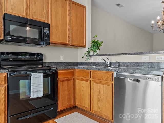 kitchen featuring a notable chandelier, sink, light hardwood / wood-style flooring, and black appliances