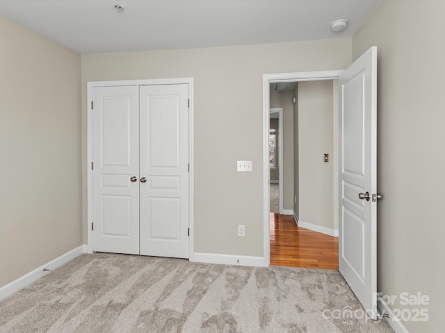 unfurnished bedroom with light colored carpet and a closet