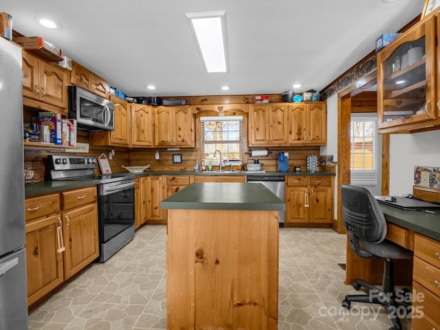 kitchen with a kitchen island, a healthy amount of sunlight, appliances with stainless steel finishes, and sink