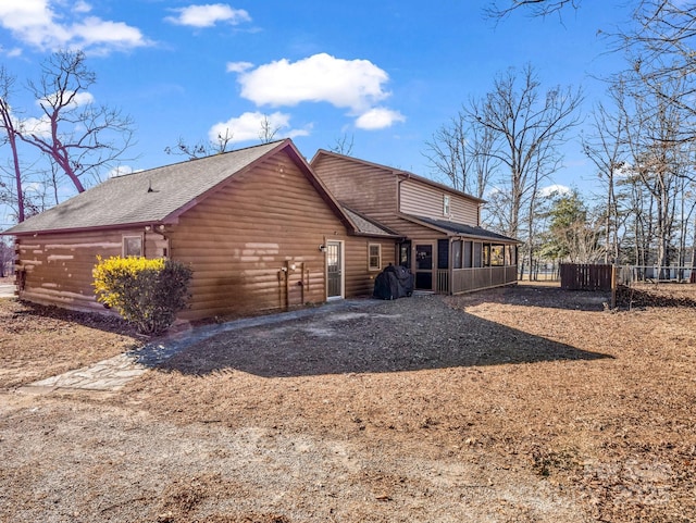 rear view of property featuring a garage and a sunroom