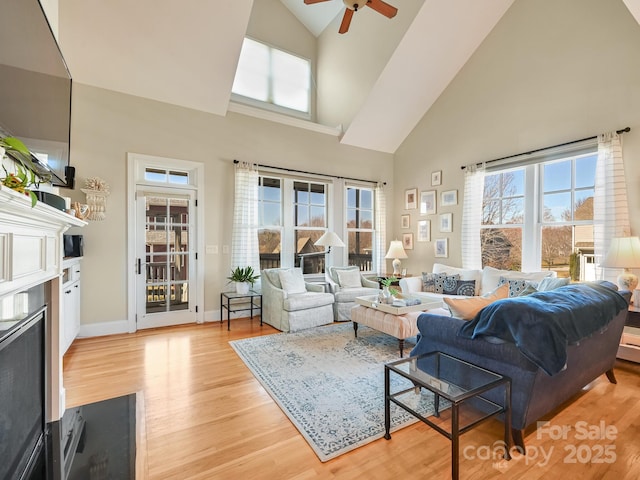 living room featuring ceiling fan, light wood-type flooring, and a high ceiling