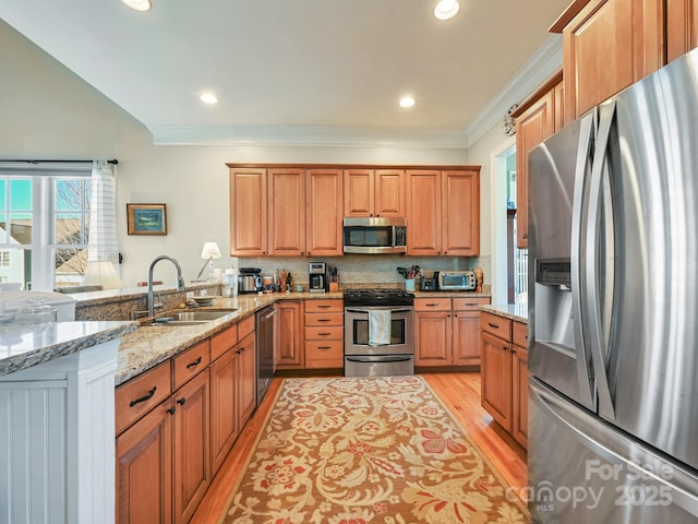 kitchen featuring appliances with stainless steel finishes, sink, light stone counters, light hardwood / wood-style floors, and crown molding