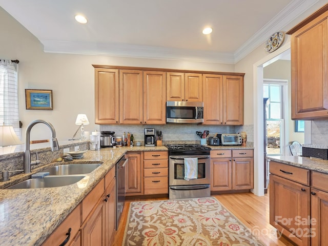 kitchen featuring sink, appliances with stainless steel finishes, tasteful backsplash, light stone counters, and light hardwood / wood-style floors