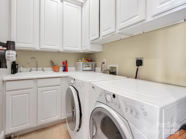 laundry area featuring sink, light tile patterned floors, washing machine and dryer, and cabinets