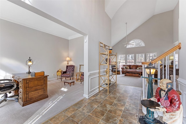 foyer with ceiling fan, dark carpet, and a high ceiling