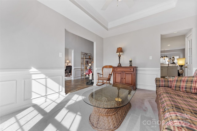 living room featuring crown molding, light carpet, ceiling fan, and a tray ceiling