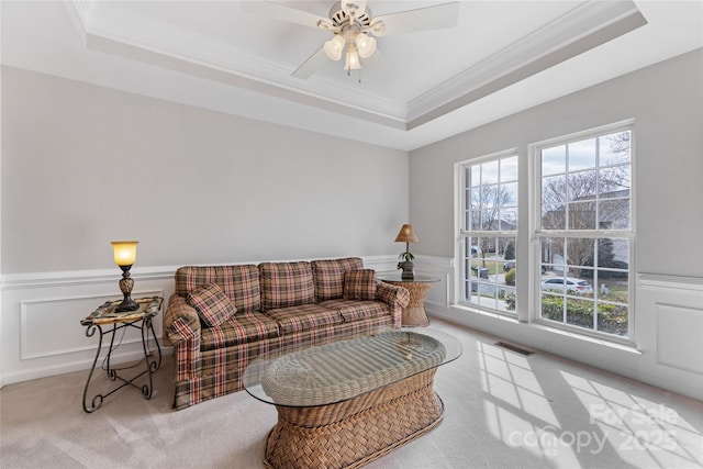 living room featuring crown molding, light colored carpet, a raised ceiling, and ceiling fan