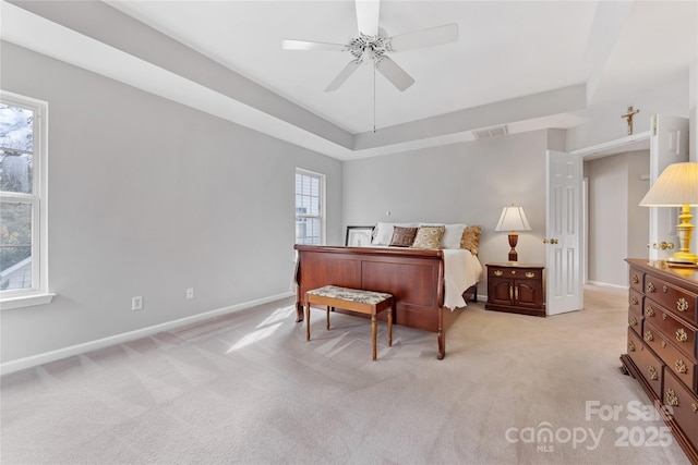 carpeted bedroom with ceiling fan and a raised ceiling