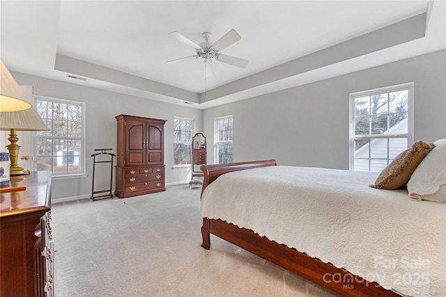 carpeted bedroom with ceiling fan and a raised ceiling