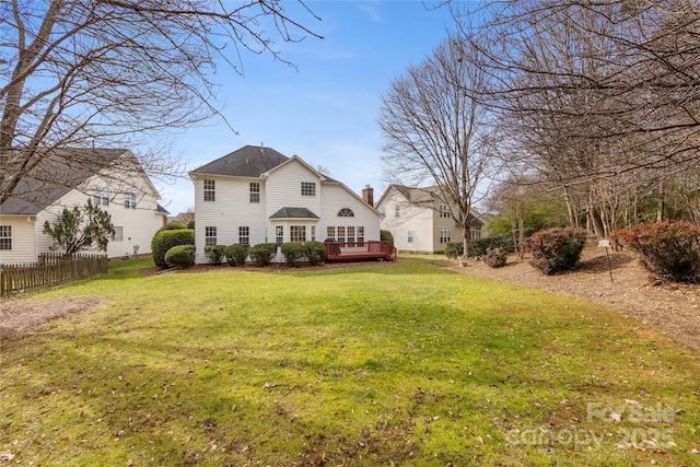 rear view of house with a wooden deck and a lawn