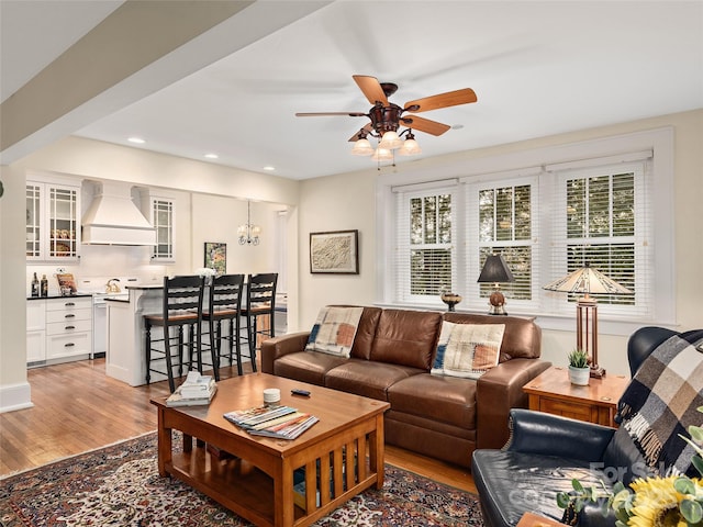 living room featuring light wood-type flooring and ceiling fan with notable chandelier