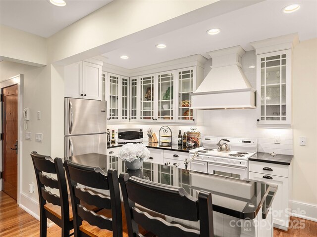 203 6th Ave W Unit 1B, Hendersonville, NC 28739 - kitchen with custom exhaust hood, white appliances, dark countertops, light wood finished floors, and recessed lighting
