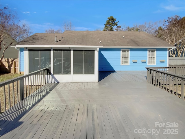 rear view of house featuring a sunroom and a wooden deck