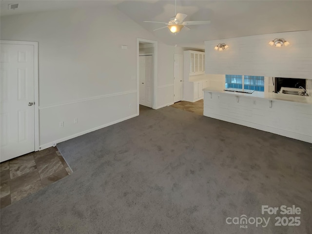 unfurnished living room with vaulted ceiling, dark colored carpet, and ceiling fan