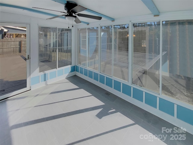 unfurnished sunroom featuring ceiling fan and beamed ceiling