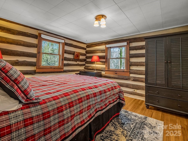 bedroom with log walls and light hardwood / wood-style flooring