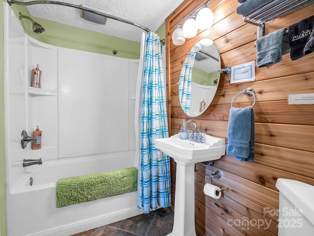 bathroom featuring shower / bath combo, tile patterned flooring, a textured ceiling, toilet, and wood walls