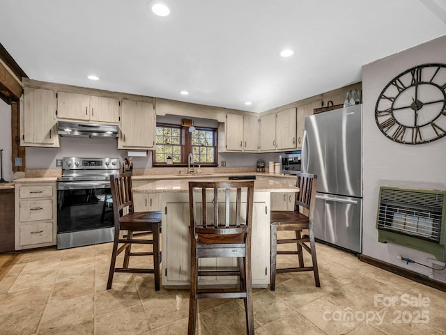 kitchen featuring sink, a breakfast bar area, stainless steel appliances, heating unit, and a kitchen island