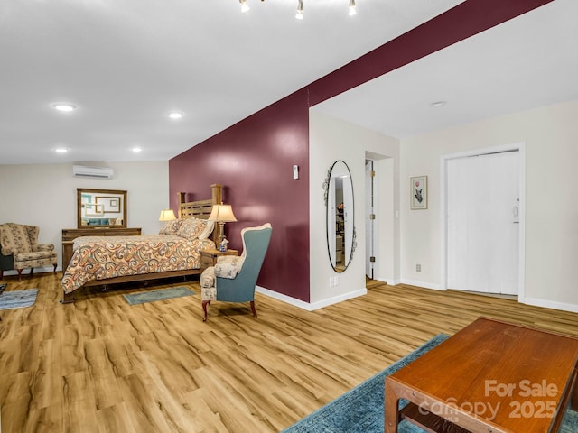 bedroom with a wall mounted air conditioner and hardwood / wood-style floors