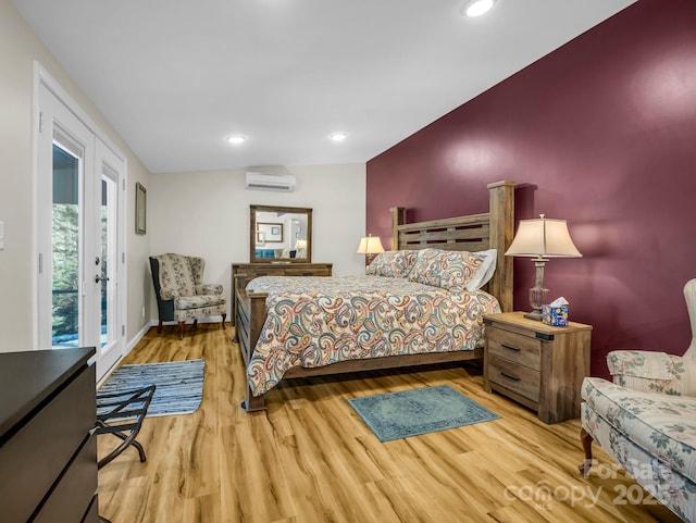 bedroom with access to exterior, a wall unit AC, and light hardwood / wood-style floors