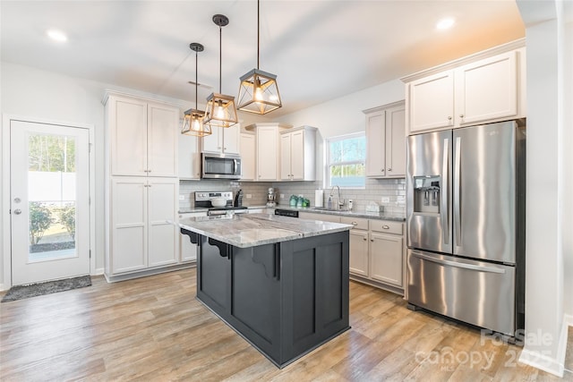 kitchen with light stone countertops, a kitchen island, stainless steel appliances, a kitchen breakfast bar, and hanging light fixtures