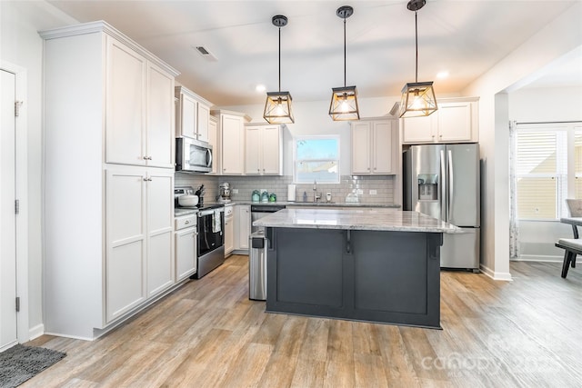 kitchen featuring stainless steel appliances, a center island, hanging light fixtures, and sink