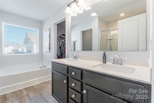 bathroom with plus walk in shower, wood-type flooring, and vanity