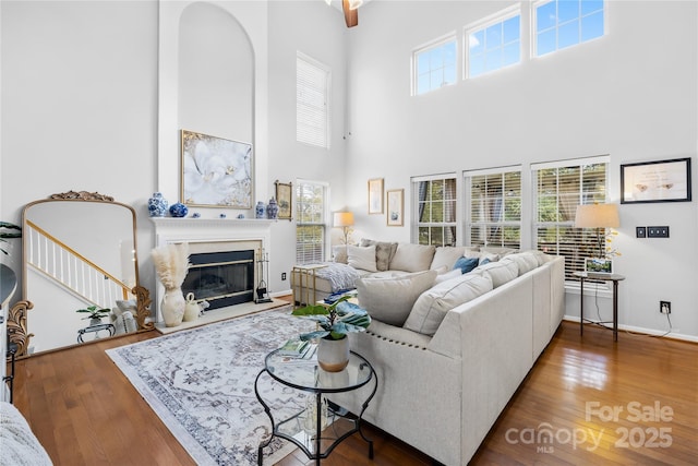 living room with a fireplace, dark hardwood / wood-style floors, and a towering ceiling