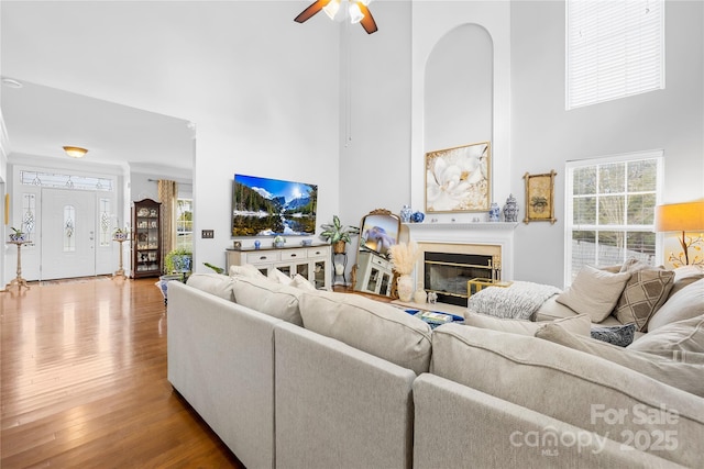 living room featuring hardwood / wood-style flooring, ceiling fan, and a high ceiling