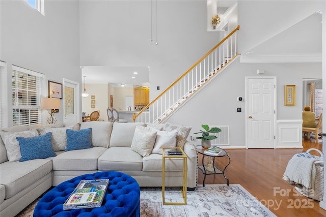 living room with crown molding, wood-type flooring, and a high ceiling