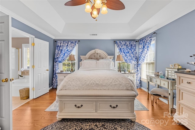 bedroom featuring ceiling fan, a raised ceiling, and light wood-type flooring