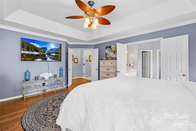 bedroom with crown molding, ensuite bath, ceiling fan, dark hardwood / wood-style flooring, and a raised ceiling